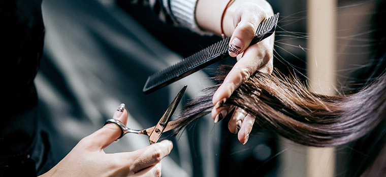 Peluquero usando tijeras y peine para cortar el cabello del hombre